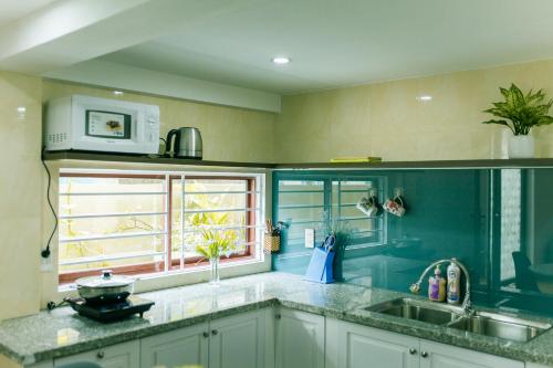 a green kitchen with a sink and a window at Tùng Homestay in Hue