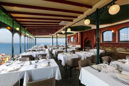 Un restaurante con mesas y sillas blancas y el océano. en Sultanahmet Palace Hotel, en Estambul