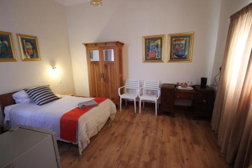 
a bedroom with a bed, desk, chair, and lamp at Donkin Country House in Beaufort West
