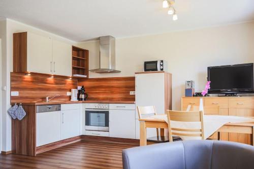 a kitchen with white cabinets and a table and a tv at Buedlfarm-West in Sahrensdorf