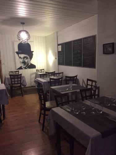 a restaurant with tables and a man with a hat on the wall at Hôtel La Tour D'Auvergne in Pont-lʼAbbé