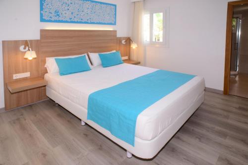 a bedroom with a large bed with blue pillows at Cala Llenya Resort Ibiza in Cala Llenya