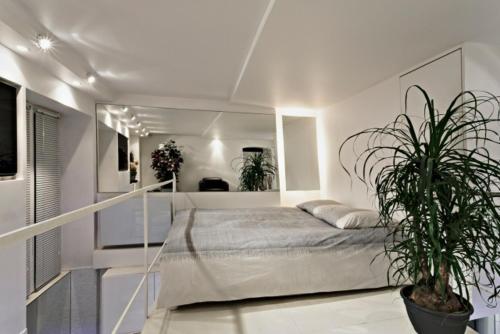 a white bedroom with a bed and a potted plant at Stylish,luxury duplex Paris city center in Paris