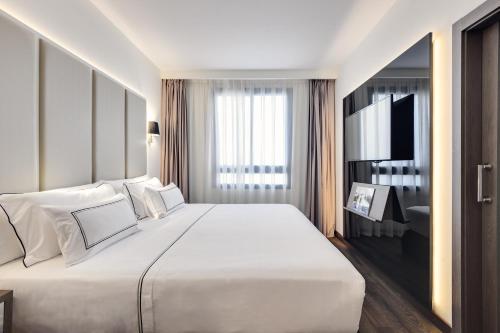 a bedroom with a large white bed and a television at Melia Madrid Serrano in Madrid