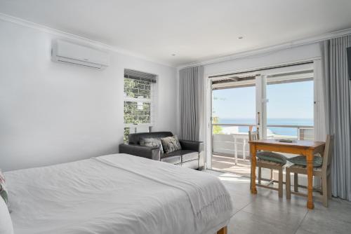 Camps Bay Studio Guesthouse - Studio في كيب تاون: غرفة نوم بسرير ومكتب ونافذة