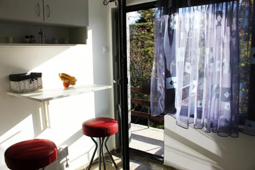 a kitchen with red stools in front of a window at Bankya Guest House - Sofia in Bankya