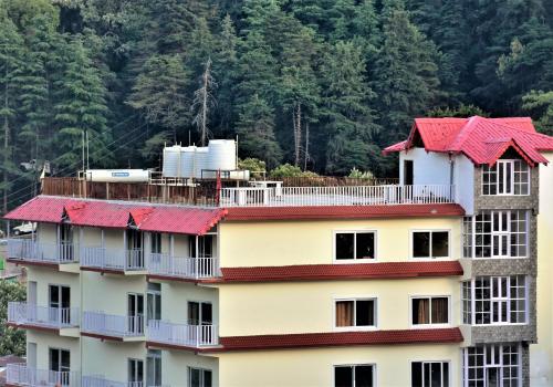 a building with red roofs with a mountain in the background at Hotel Vista Bhowali, Nainital - Vegetarian in Bhowāli