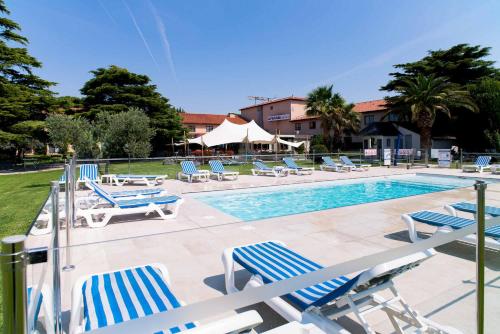 una piscina con tumbonas azules y blancas y una piscina en Hôtel Ariane, en Fos-sur-Mer