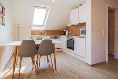 a kitchen with white cabinets and a table and chairs at Buedlfarm-Scheune in Sahrensdorf