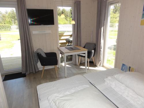 Tornby Strand Camping Cottages في هيرتسهلس: غرفة نوم بسرير وطاولة مع تلفزيون
