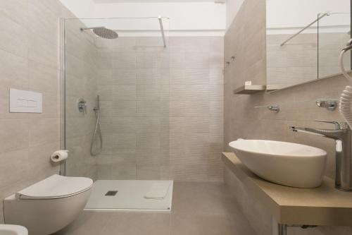 y baño con aseo, lavabo y ducha. en Hotel Ispinigoli, en Dorgali
