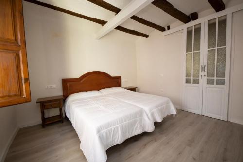 a bedroom with a large white bed with a wooden headboard at Casa Rural Pradas in Montanejos