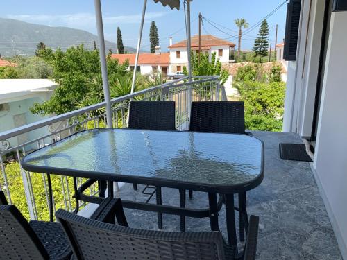 a glass table and chairs on a balcony at Magdalini House in Paralio Astros