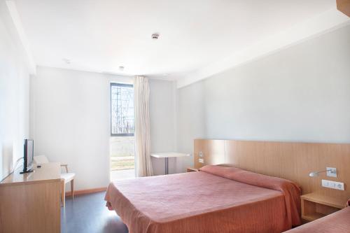 een slaapkamer met 2 bedden en een groot raam bij AS Hoteles Ponferrada in Columbrianos