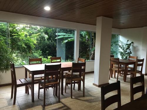 a dining room with tables and chairs and a large window at Pousada Sereia Dourada in Itacaré