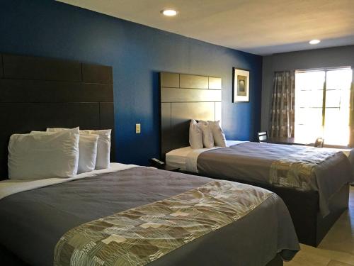 2 camas en una habitación de hotel con paredes azules en Americas Best Value Inn Denham Springs, en Denham Springs