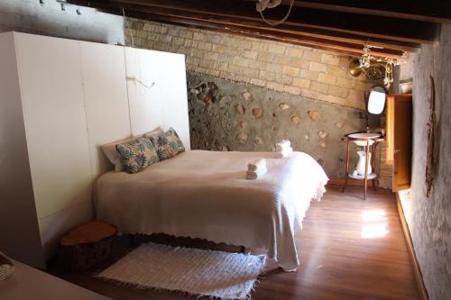 1 dormitorio con cama y pared de ladrillo en CAL CUP casa reposo vacacional, en Bisbal del Penedès