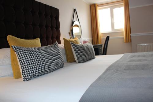 a bedroom with a bed with four pillows on it at Badgers Mount Hotel in Earl Shilton