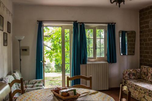 ソヴァナにあるPodere Le Chiuseのリビングルーム(テーブル付)、青いカーテン付きの窓