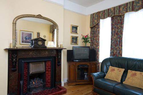 a living room with a fireplace and a tv at Griffin Lodge Guesthouse in Galway
