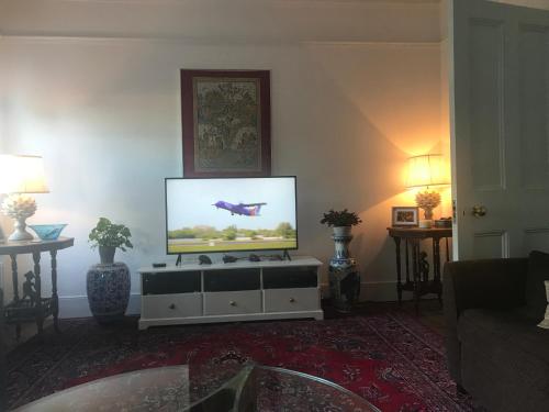 a living room with a flat screen tv sitting on a cabinet at Holmewood Homestay in London