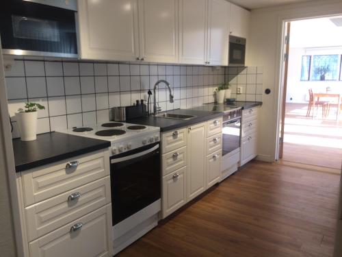 a kitchen with white cabinets and a sink and a stove at EFS Höllviksstrand in Höllviken