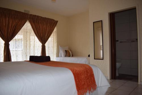 a hotel room with two beds and a window at Moye Guest House in Benoni