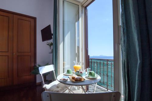 a table with a plate of food on a balcony at NapoliCentro Mare - Sea View Rooms & Suites in Naples