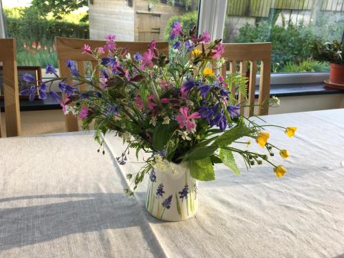 a vase filled with purple and yellow flowers on a table at East Hillerton House in Crediton