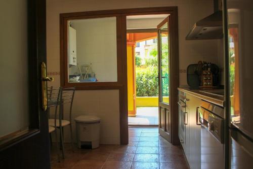 una cocina con una puerta que da a una cocina con mesa en HAA001) Apartamento moderno con jardín., en Ayamonte