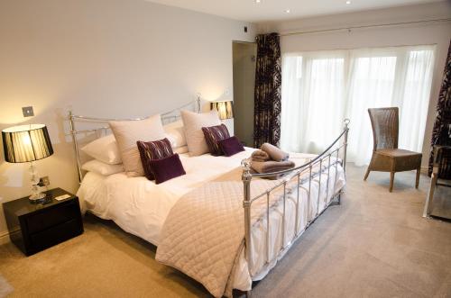 a bedroom with a bed with white sheets and purple pillows at Contemporary Barn Conversion in Stunning Setting in Kirkby Lonsdale