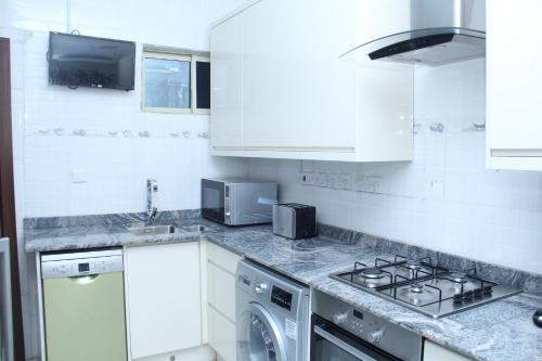 cocina blanca con lavadora y fregadero en SSCFG APTMS & SUITES - SAMMY's PLACE, en Lagos