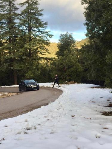 a person crossing a road with a car in the snow at Villa ain soltan in Imouzzer Kandar