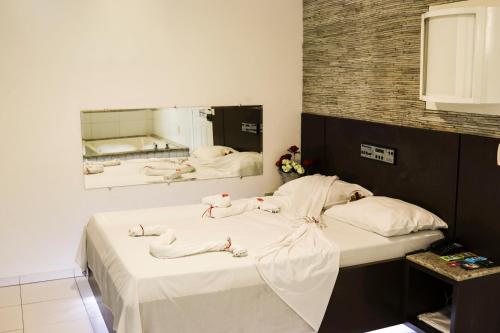 1 Schlafzimmer mit 2 Betten mit weißer Bettwäsche und einem Spiegel in der Unterkunft MOTEL SHAMPOO (Adult Only) in Brusque