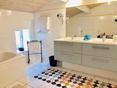 een witte badkamer met een wastafel, een bad en een bad bij Du Côté de l'Ombrière in Geay