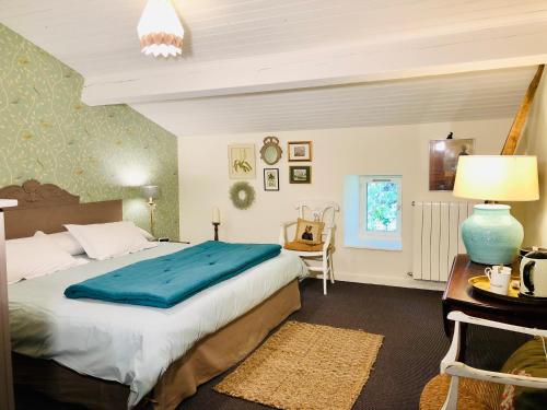 une chambre avec un grand lit avec une couverture bleue dans l'établissement Du Côté de l'Ombrière, à Geay