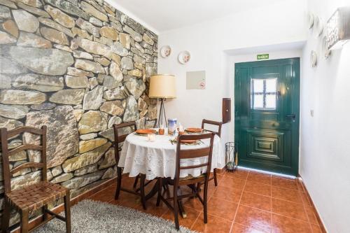 comedor con mesa y pared de piedra en Casa dos Moinhos Velhos, en Brinches