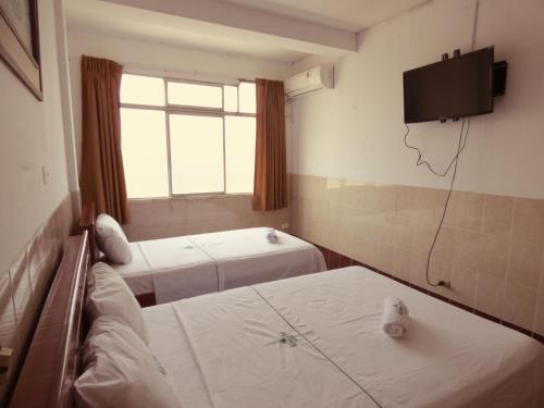 a room with two beds and a tv on the wall at Hotel Aloe Uka in Iquitos