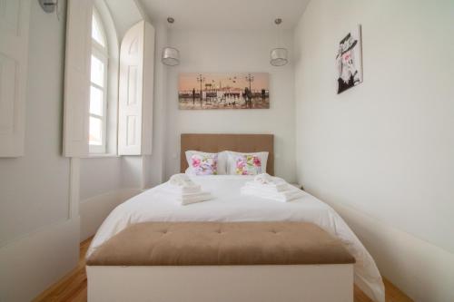 - une chambre blanche avec un lit avec un pouf dans l'établissement Passeio da Avenida - Central Avenue Apartment with Elevator, à Viana do Castelo