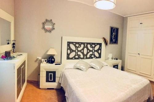 a white bedroom with a white bed and a mirror at Precioso apartamento a pie de playa en la nueva Milla de Oro entre Estepona y Marbella in Estepona