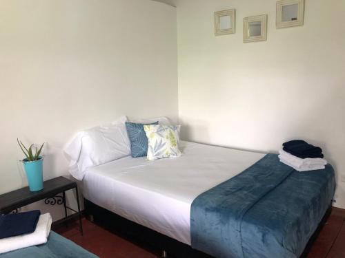 a bedroom with a white bed with a blue blanket on it at Finca Hotel Brasilia in La Tebaida