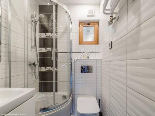 a white bathroom with a toilet and a sink at Domki Morska in Rewa