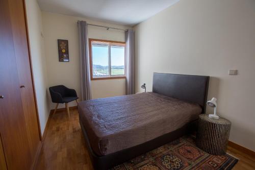 1 dormitorio con 1 cama, 1 silla y 1 ventana en Afife T2 - Bouça Cabrita Residence en Afife