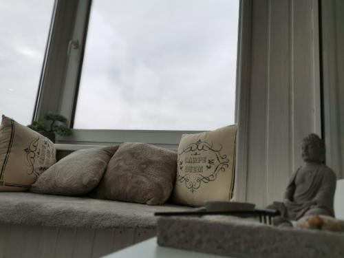 a couch with pillows sitting next to a window at Cosy center Apartment in Klaipėda