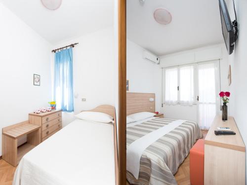 a bedroom with a bed and a desk and a mirror at Hotel Meeting in Cesenatico