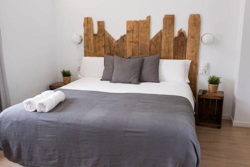 een slaapkamer met een groot bed met een houten hoofdeinde bij GOMEZ ROOMS in Xàtiva