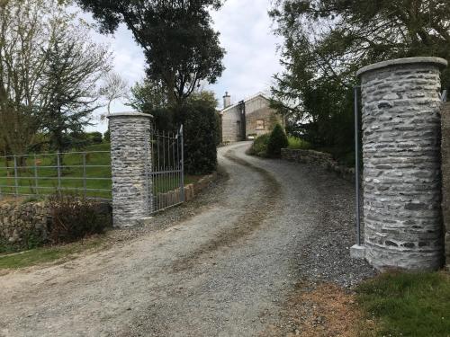 a dirt road with two stone pillars next to a fence at Seaside Cottage in Wexford