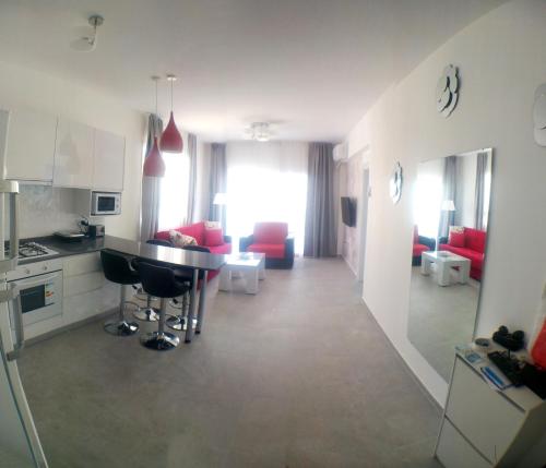 a kitchen and living room with red chairs and a table at Angel's Apartment at Caesar Resort in Trikomo