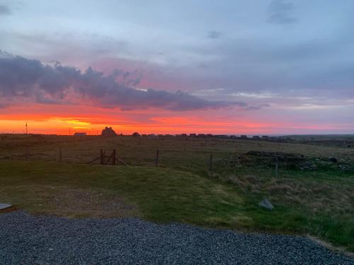 a sunset in the middle of a field with a fence at 18 Cross Skigesrta Road in Swanibost