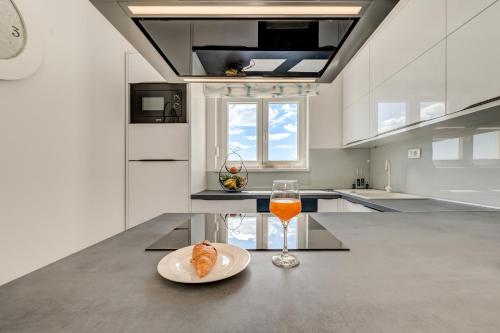 um copo de sumo de laranja e um prato de comida no balcão da cozinha em Modern 4* luxury apartment in center em Trogir